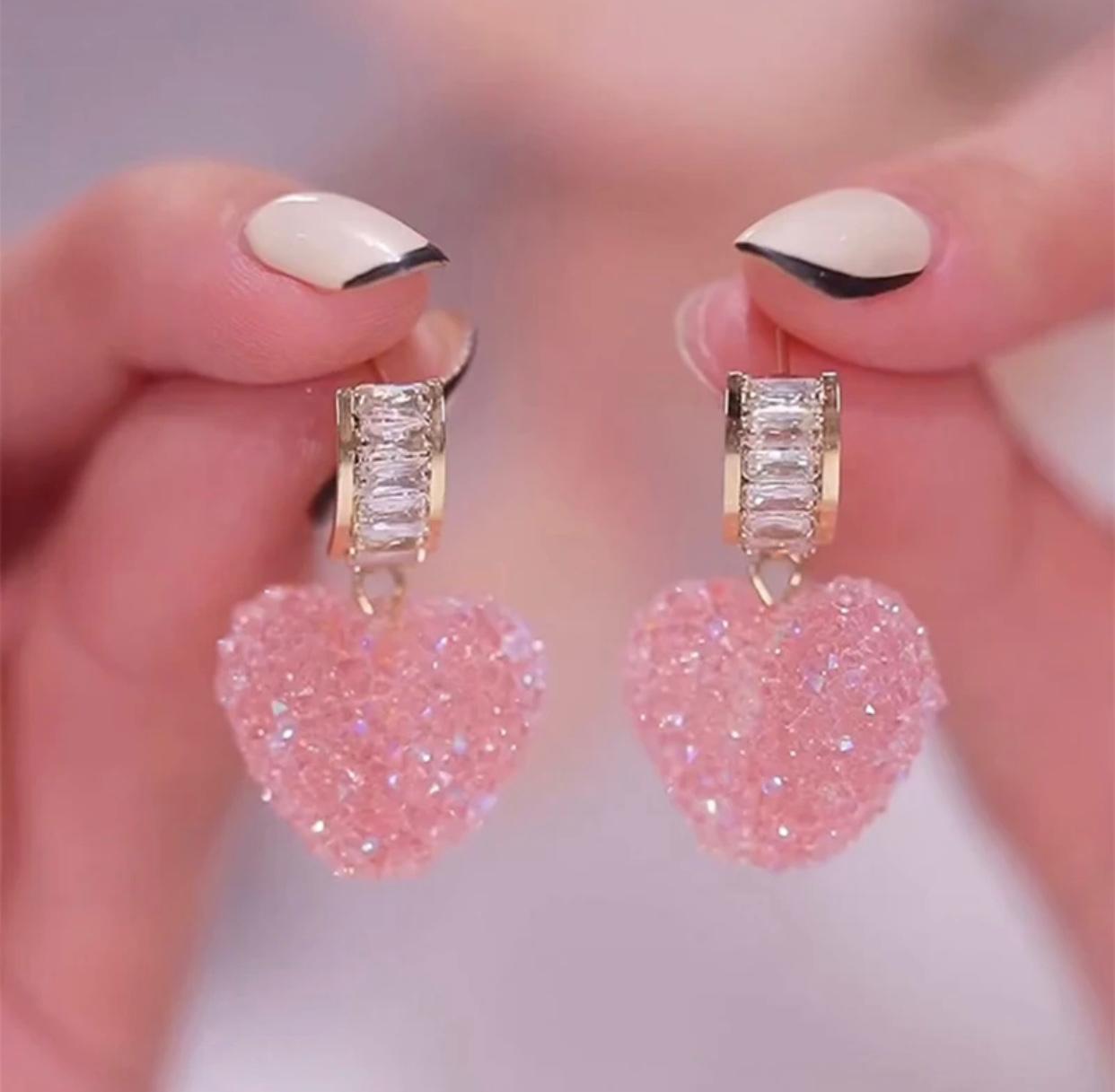 A pair of earrings featuring pink crystals arranged in a fudge like pattern