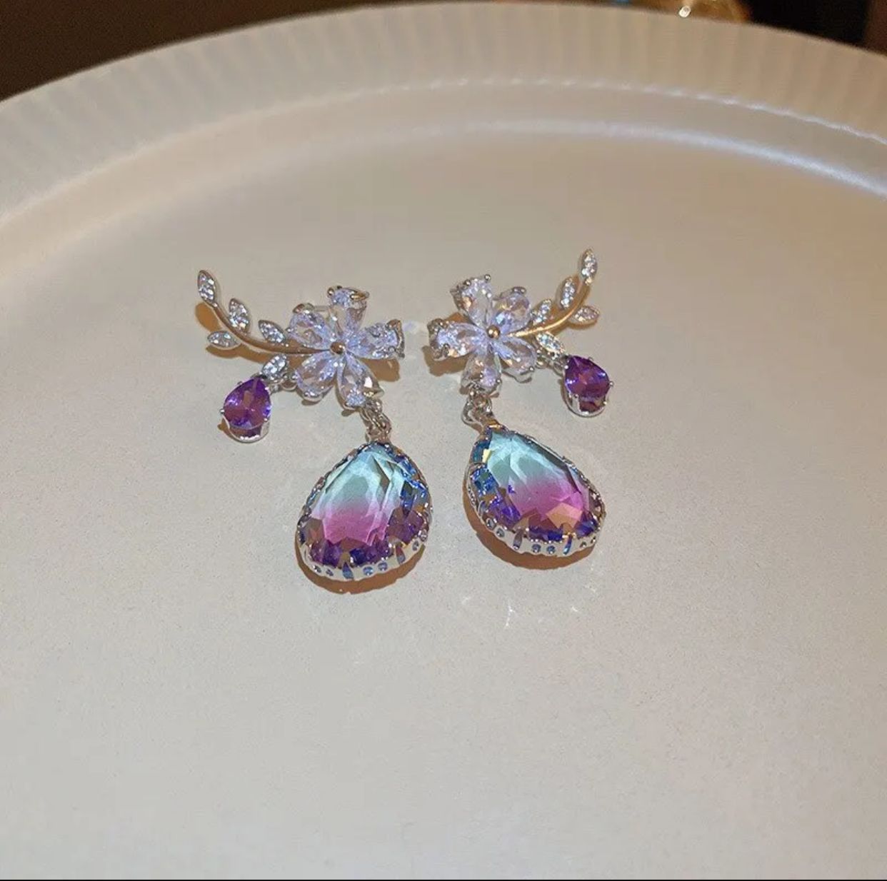 A stunning pair of earrings featuring a floral design with purple zircon stones.